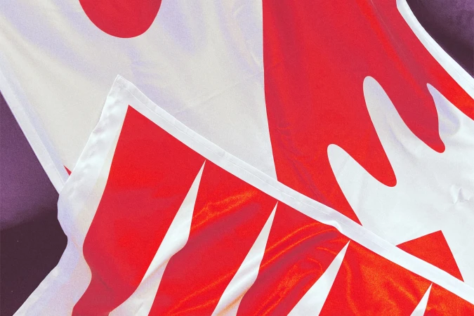 Close-up abstract view of a red and white patterned textile banner with triangular shapes and wavy edges, creating a textured, vibrant display.
