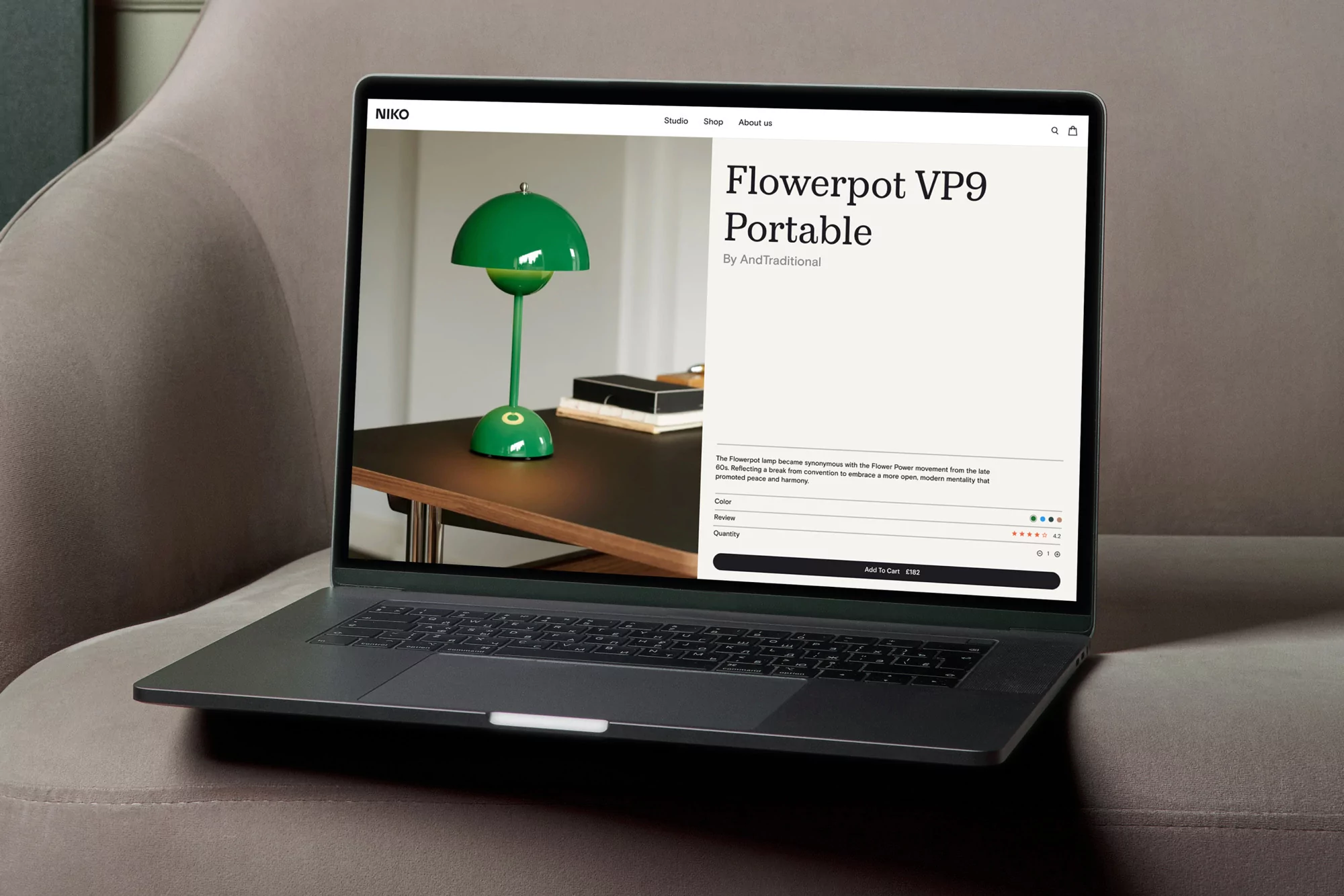 Laptop displays a product page for a green Flowerpot VP9 Portable lamp, on a grey upholstered surface, showcasing modern design and home decor.