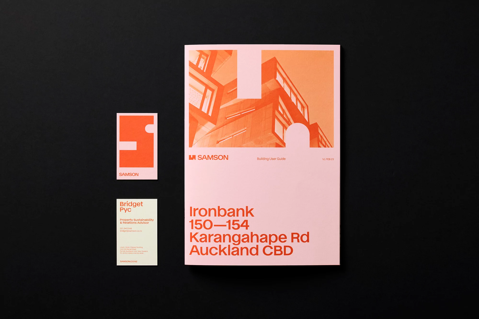 Promotional material featuring a salmon-colored building graphic on a brochure next to matching business cards and logo against a black background.