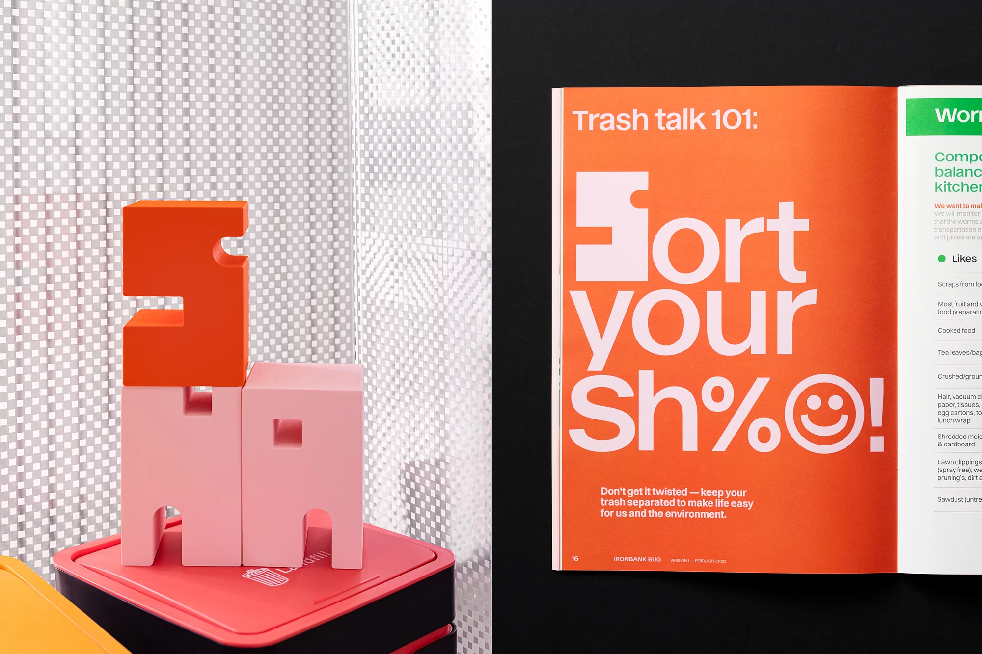 Still life of orange and pink toy blocks stacked on a red storage container with an open magazine on a black surface nearby.