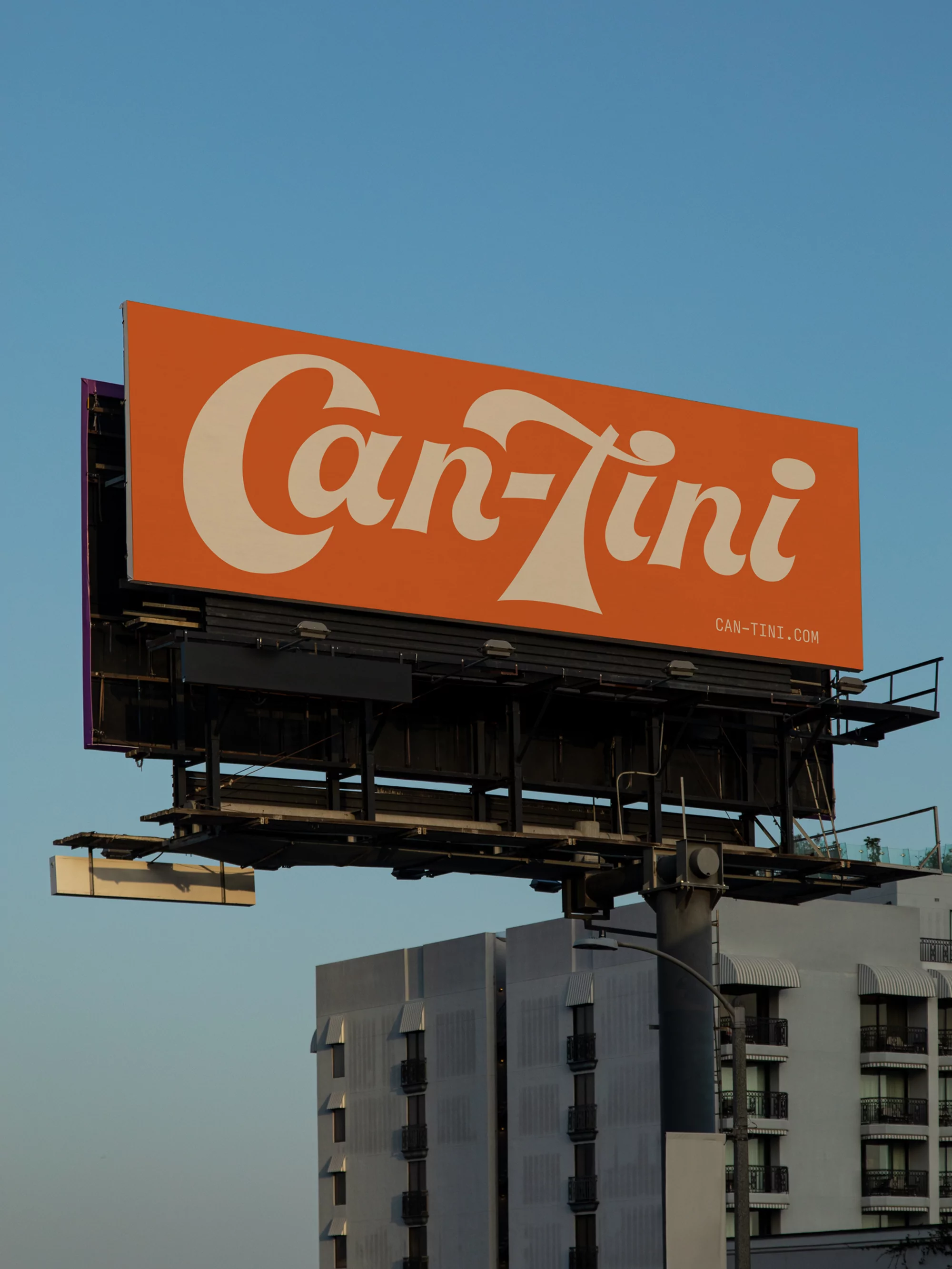 Eye-level, outdoor shot of a large, orange Can-Tini billboard with white retro font against a clear blue sky and buildings.