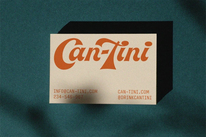 Close-up of a business card with a vintage-style orange logo 'Can-Tini' against a dark teal textured background with soft shadow.
