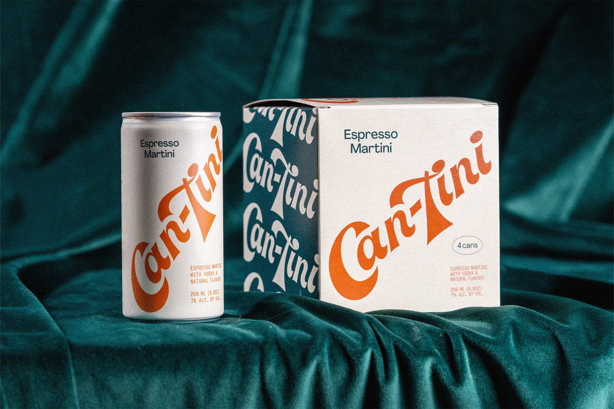 An Espresso Martini beverage can and its matching cardboard packaging set against a textured dark teal fabric background
