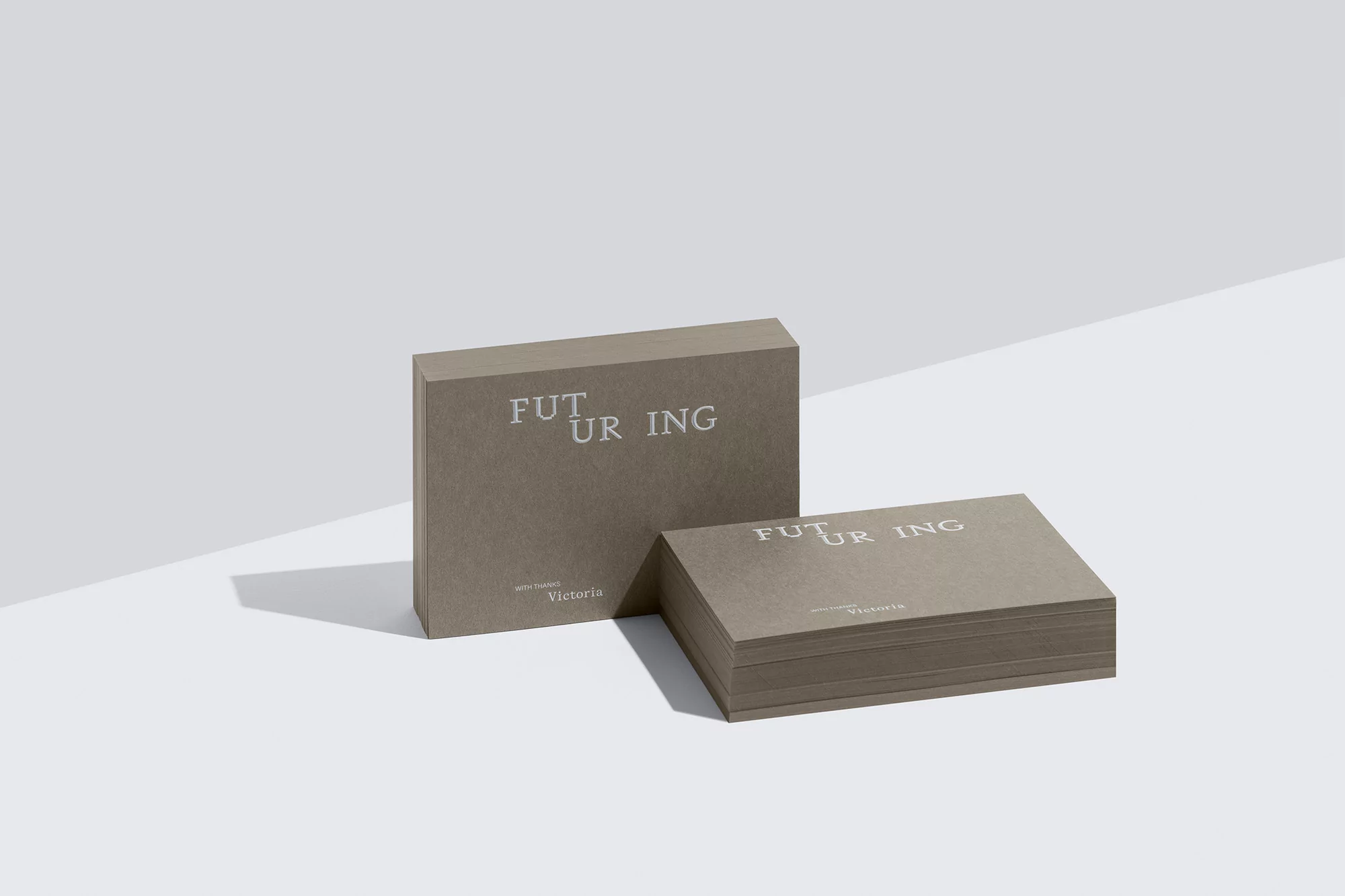 Minimalist product shot of a tan box and stack of paper cards with modern typography on a white background with soft shadows.