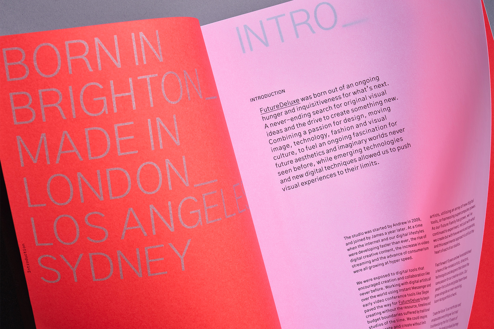 Open pages feature typography on a pink and red background. The left page lists global cities; the right page features an introduction.