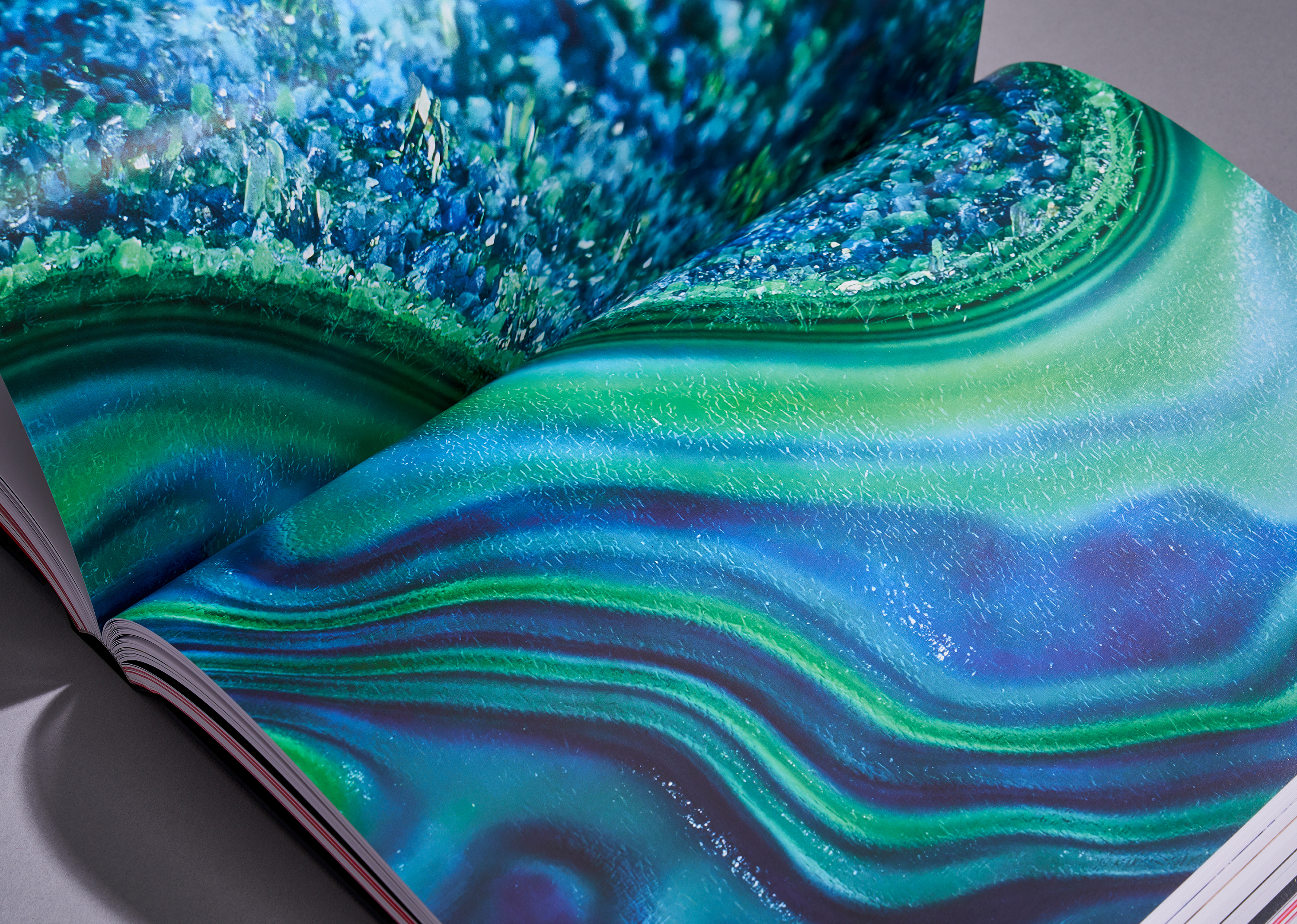 Open book displaying a detailed full-page photograph of green and blue concentric bands with crystal formations on top.