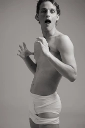 Man wearing white briefs posing with open mouth and raised hands against a grey seamless background for Markus Wiedemann.