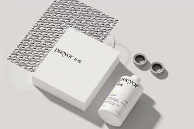 Pueyor white shopping bag and bottle with black branding on a grey surface with patterned paper and washi tape