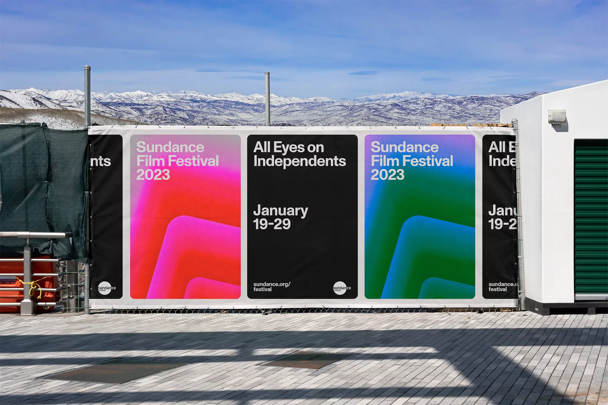Sundance Film Festival 2023 banner with pink and green designs, promoting independent films, hanging outdoors against a mountain backdrop.