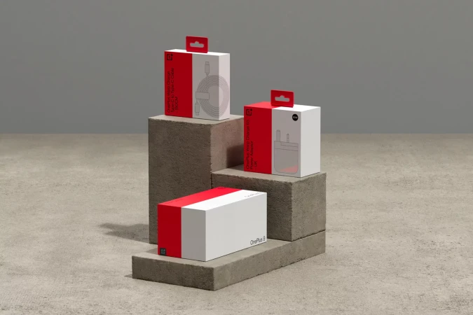 Three OnePlus product boxes are stacked on concrete blocks, including a charger, cable, and OnePlus 8 box, in a studio shot.