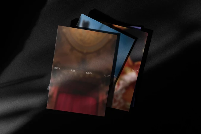 A stack of greeting cards on a black surface, featuring blurred, evocative imagery and white text, creating a sense of mystery and allure.