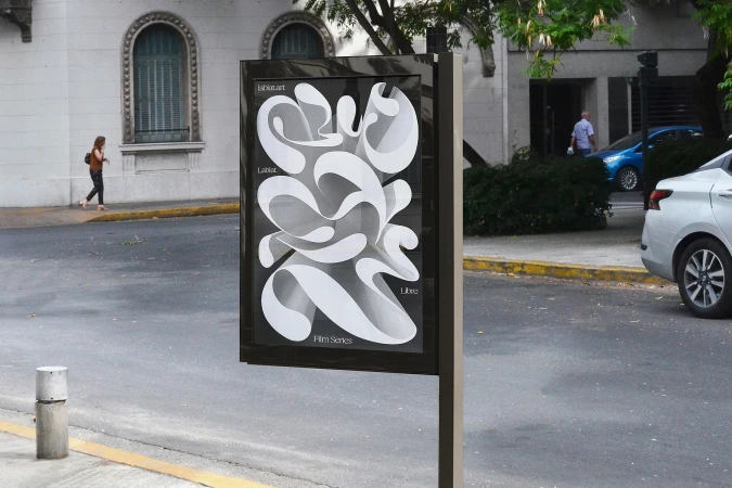 Outdoor poster with a modern white abstract design on black, advertising a LabLab Art Film Series, set in an urban environment.