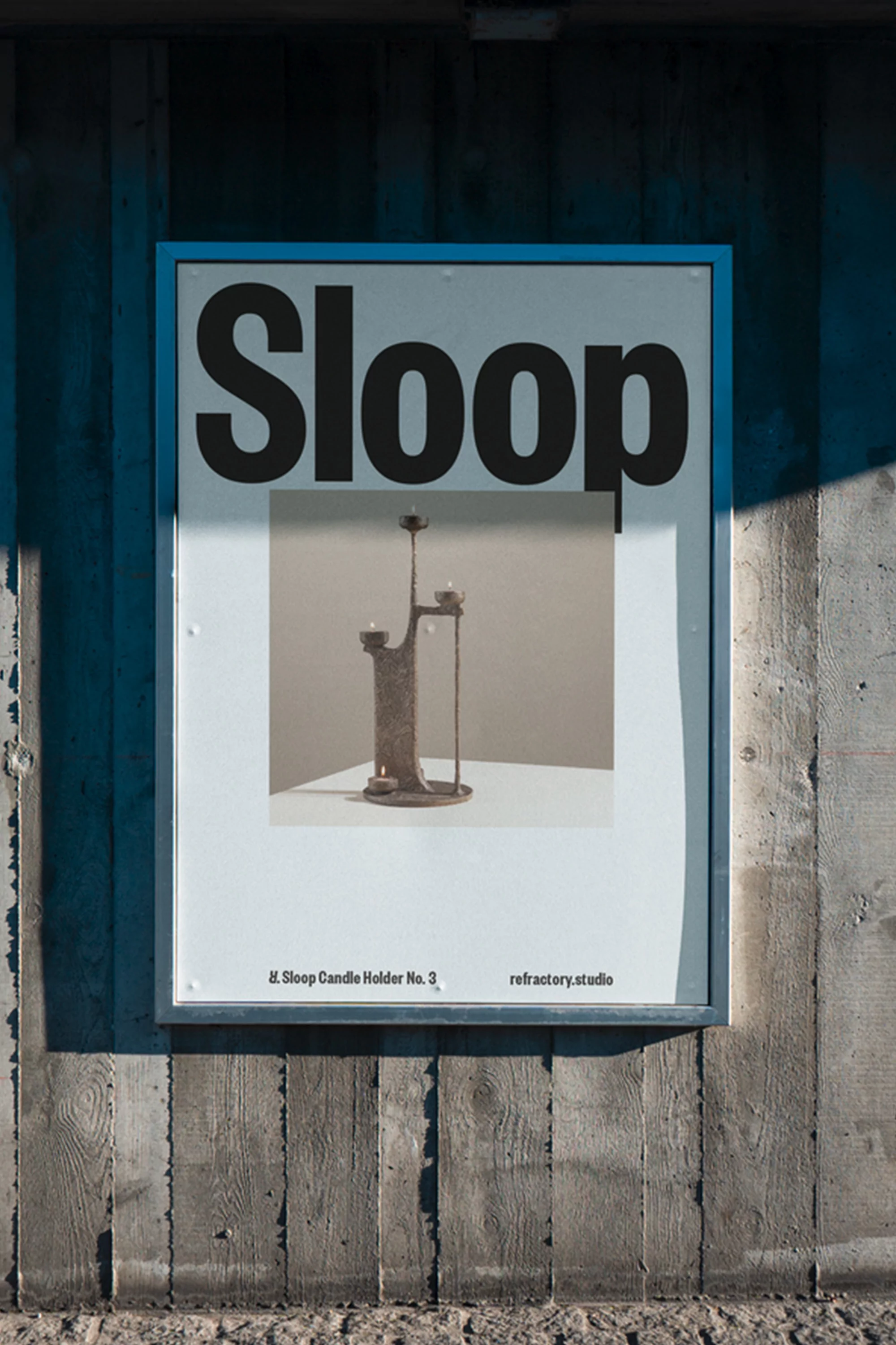 Poster on a concrete wall features 'Sloop' in bold letters and an image of a metal candle holder, advertising refractory studio.
