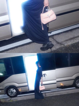 Woman in maxi dress and heels exits silver bus holding pink handbag. Asphalt ground. Lit doorway, outdoor fashion shot.