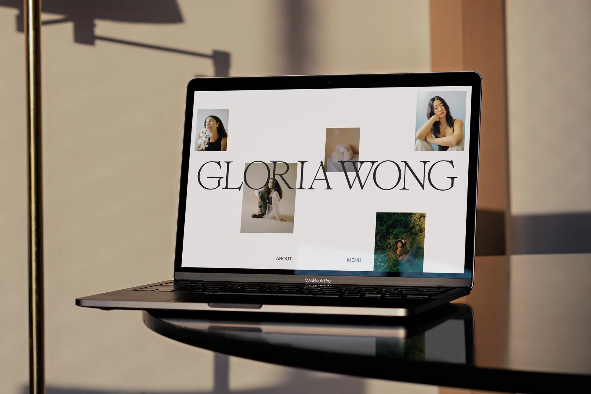 Laptop displays Gloria Wong's website in warm lighting, showcasing her portfolio and design aesthetic.