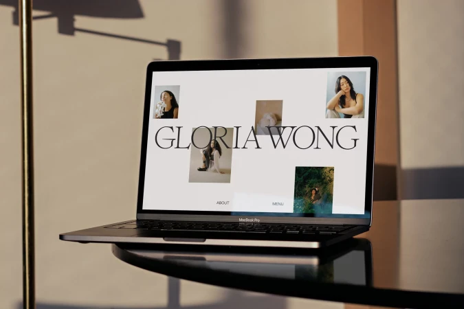 Laptop displays Gloria Wong's website in warm lighting, showcasing her portfolio and design aesthetic.