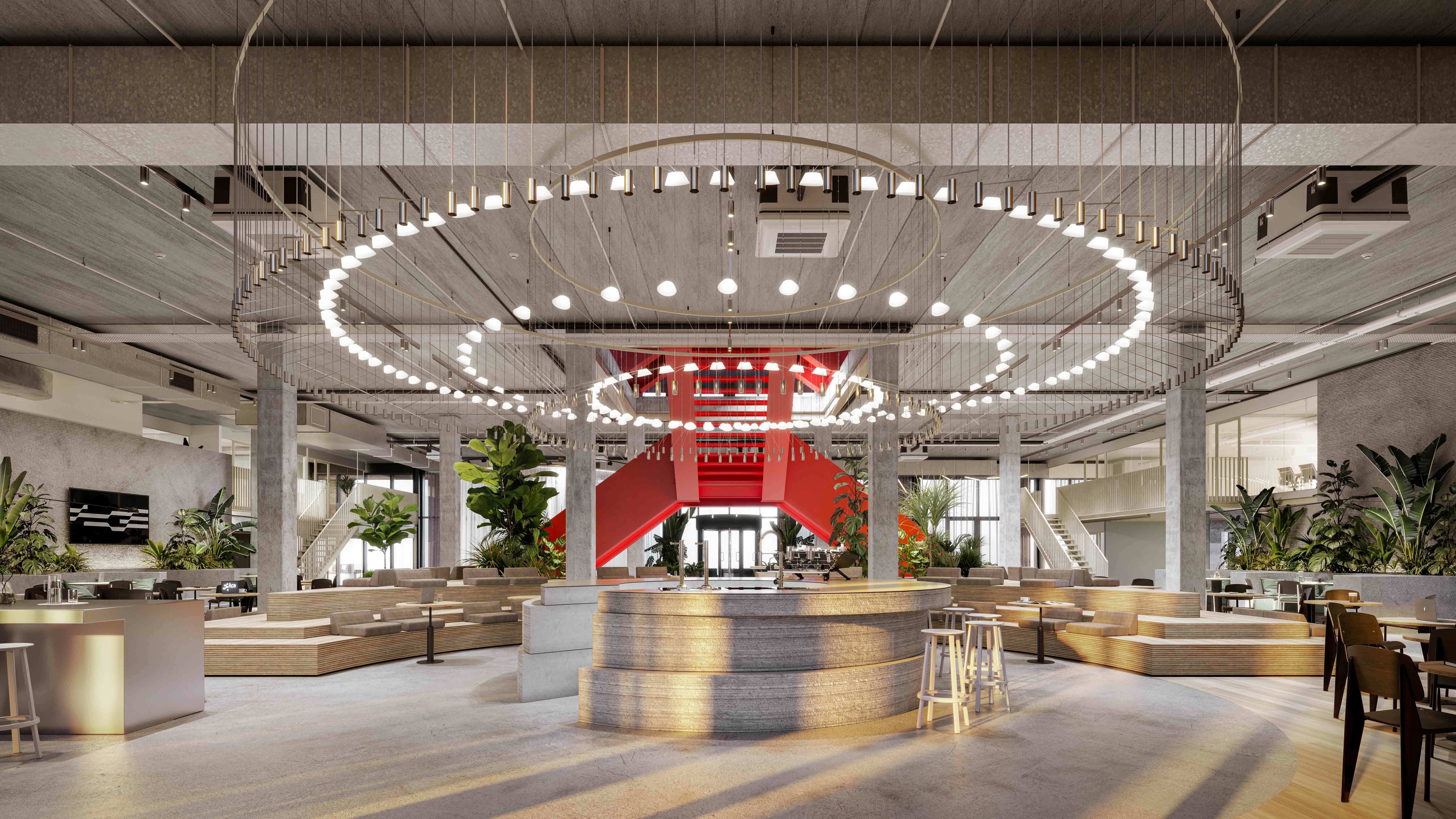 Large open office space featuring lounge areas, indoor plants, and a red staircase, illuminated by a circular chandelier.