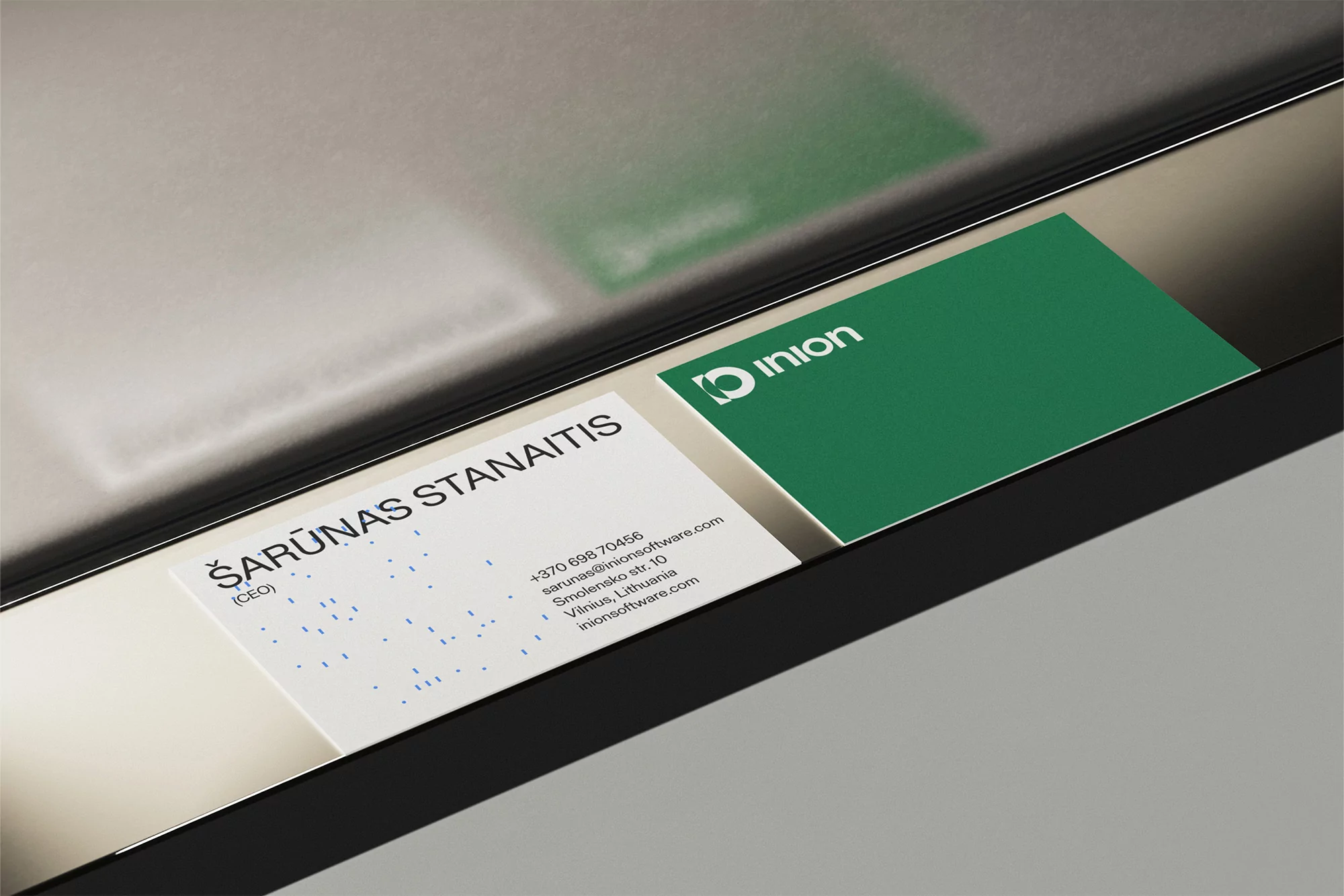 Close-up of two business cards: one white with black text, the other green with the 'inion' logo. Minimalist and modern design.