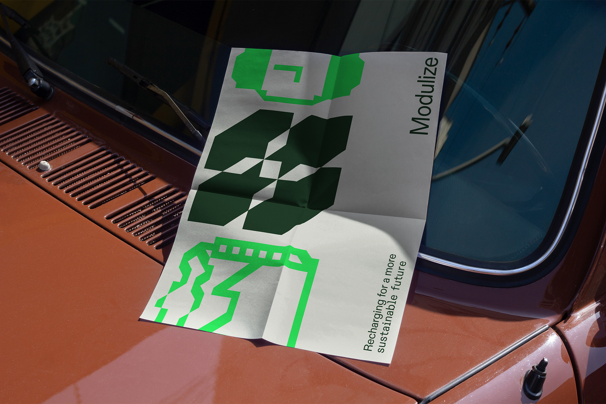 Promotional poster with green graphics on a brown car hood, featuring the text 'Modulize' and promoting sustainable future ideas.