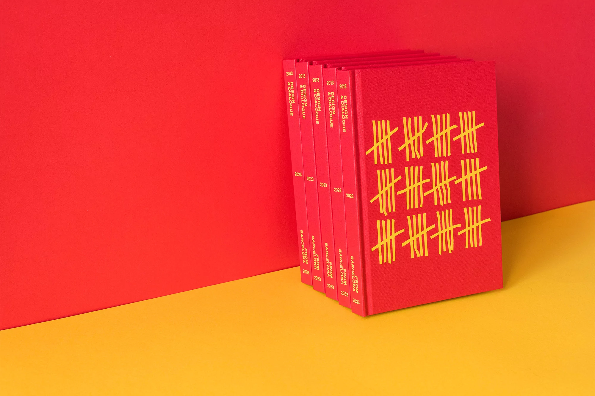 Stack of red hardcover books with tally mark design on a yellow and red surface. Close-up studio shot, colorful minimalist aesthetic.