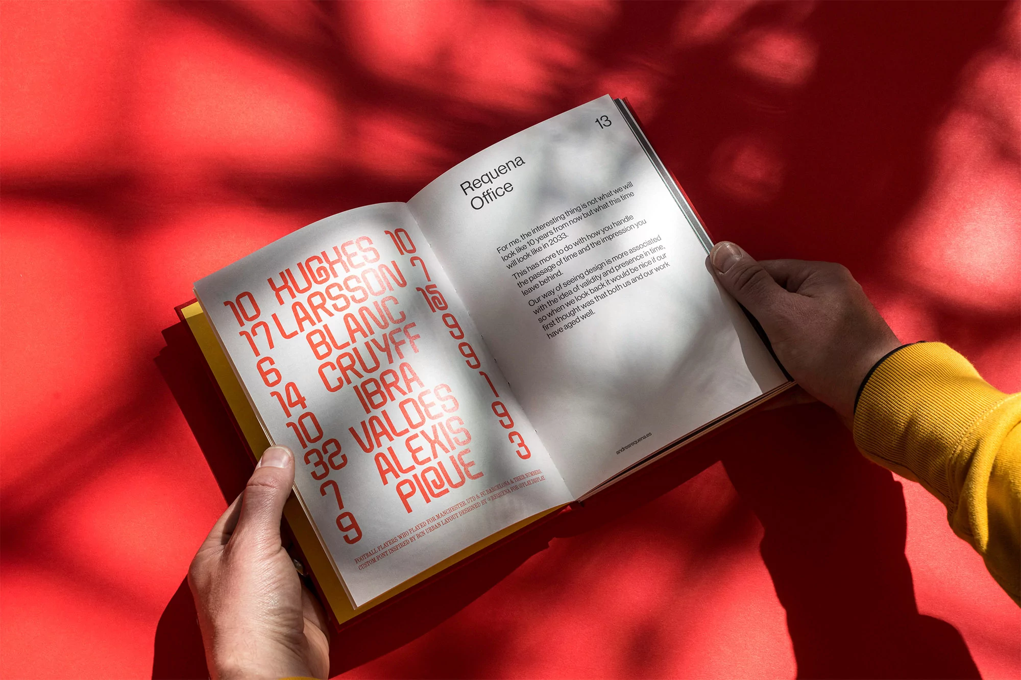 Open book featuring red typography held by hands wearing a yellow sleeve against a vibrant red background with leaf shadow patterns.