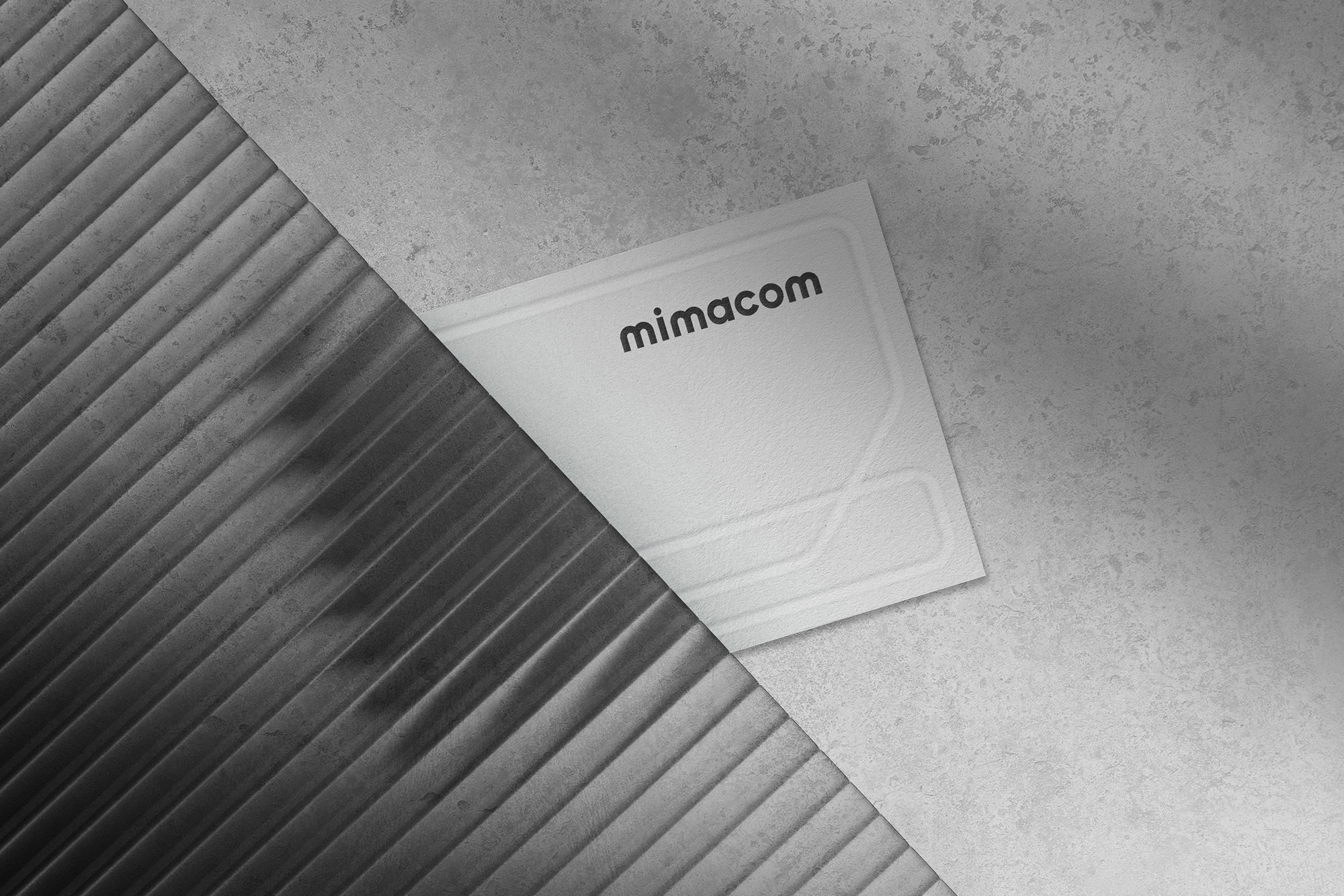 Mimacom brand identity graphic design featuring a logo card on a textured concrete and fluted surface.