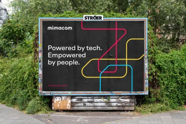 Mimacom outdoor billboard advertisement featuring bold typography and colourful abstract line graphics on a dark background.