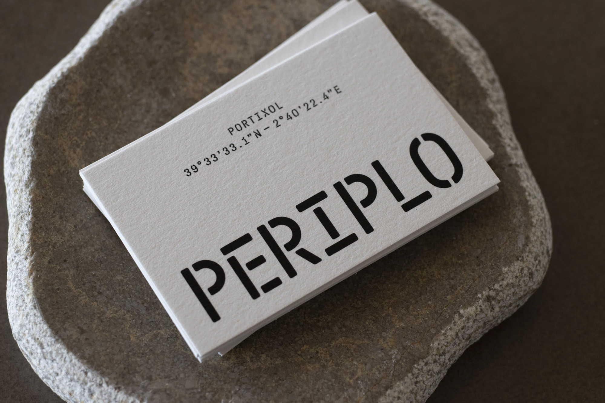 Stack of business cards with a grey stone base, featuring the name PERIPLO and location coordinates for PORTIXOL.