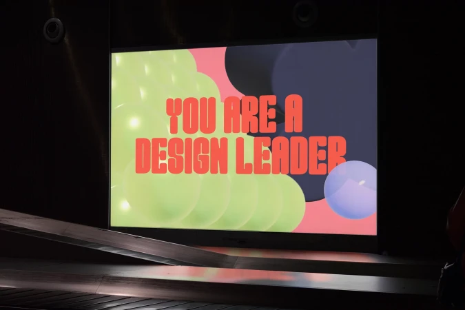 Illuminated sign displaying the message 'You are a design leader' with colourful abstract graphic elements on a dark background.