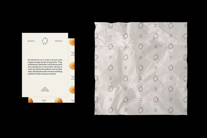 Promotional flat lay featuring a cream-colored card with food brand messaging and a light gray tissue paper patterned with the company logo.