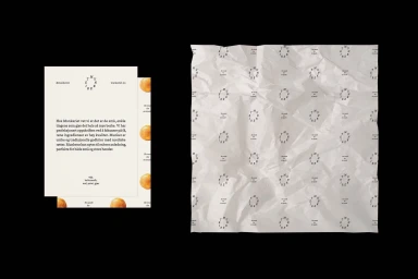 Branded stationery and crumpled printed wrapping paper showcasing typography and pastry graphics on a dark background