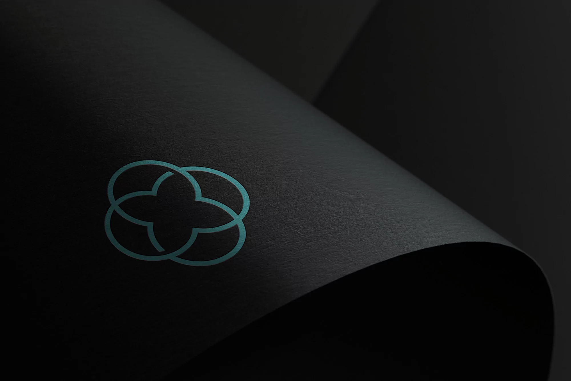Abstract clover-shaped design on a dark surface with subtle shadows, creating a minimalistic and elegant visual composition.