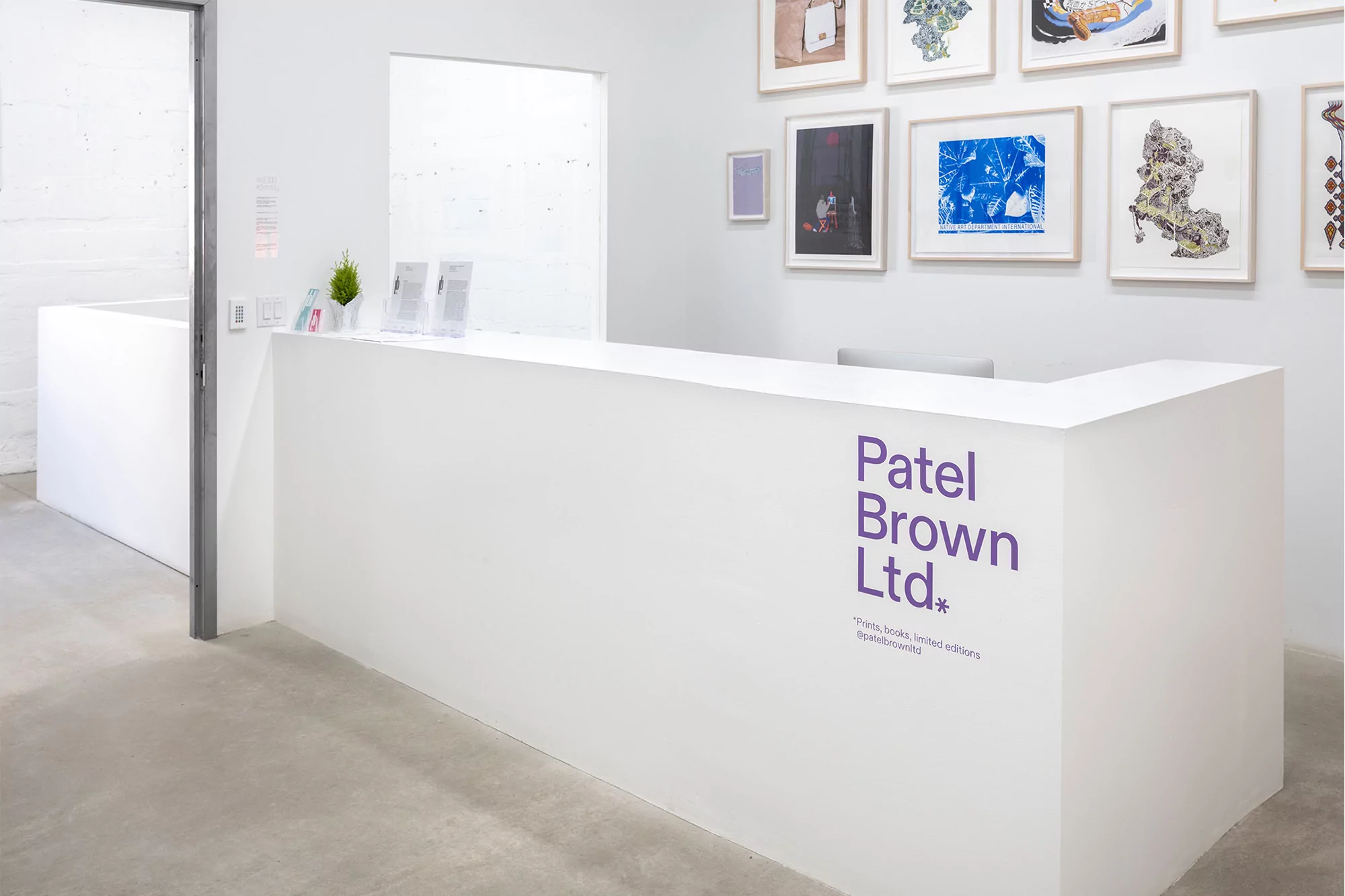 Reception area of a modern office space with white walls and a sleek counter, accented by framed art and minimalist decor.