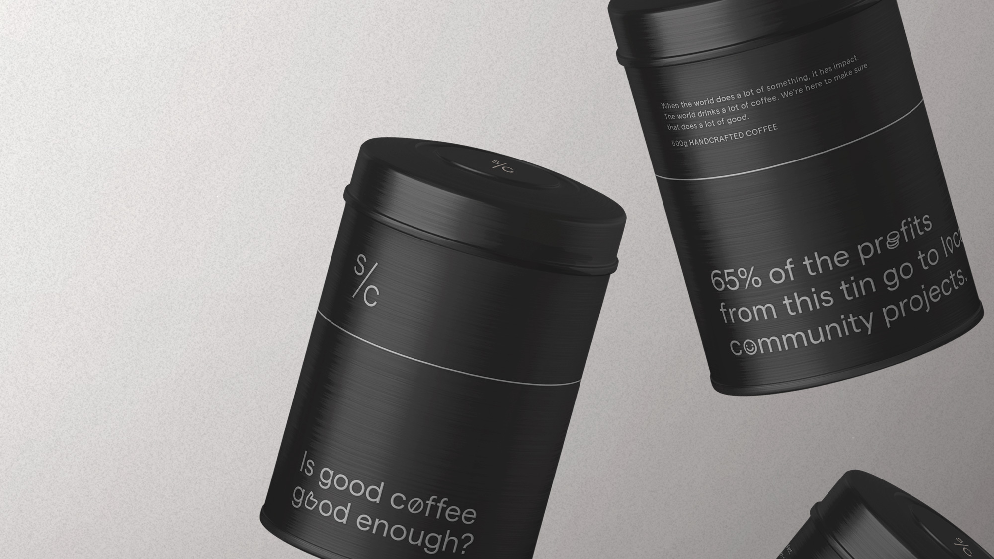 Three black tin coffee containers with branding labels, arranged on a light gray surface in a minimalist, product-focused composition.