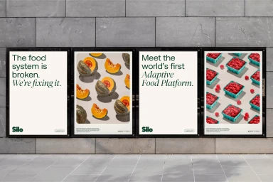 Four advertising posters for Silo mounted on a grey stone wall displaying food system messaging and product photography.