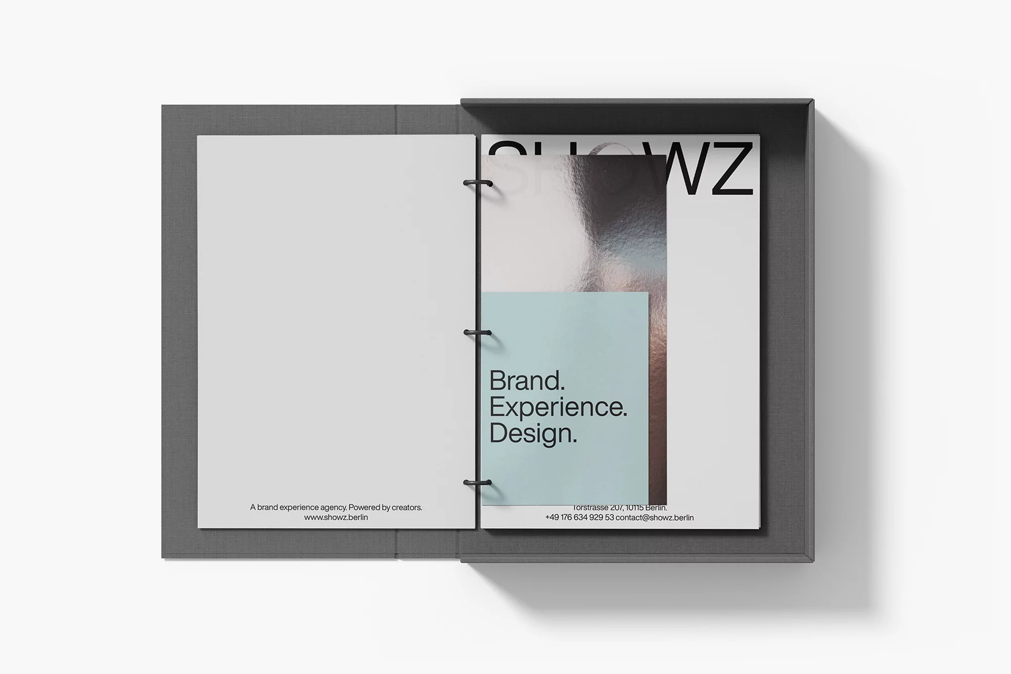 Open grey book with white pages featuring the text 'Brand. Experience. Design.' and 'show.berlin' against a plain white background.