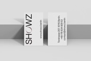Two vertical business cards displaying Showz branding and contact details set against a neutral grey studio backdrop.