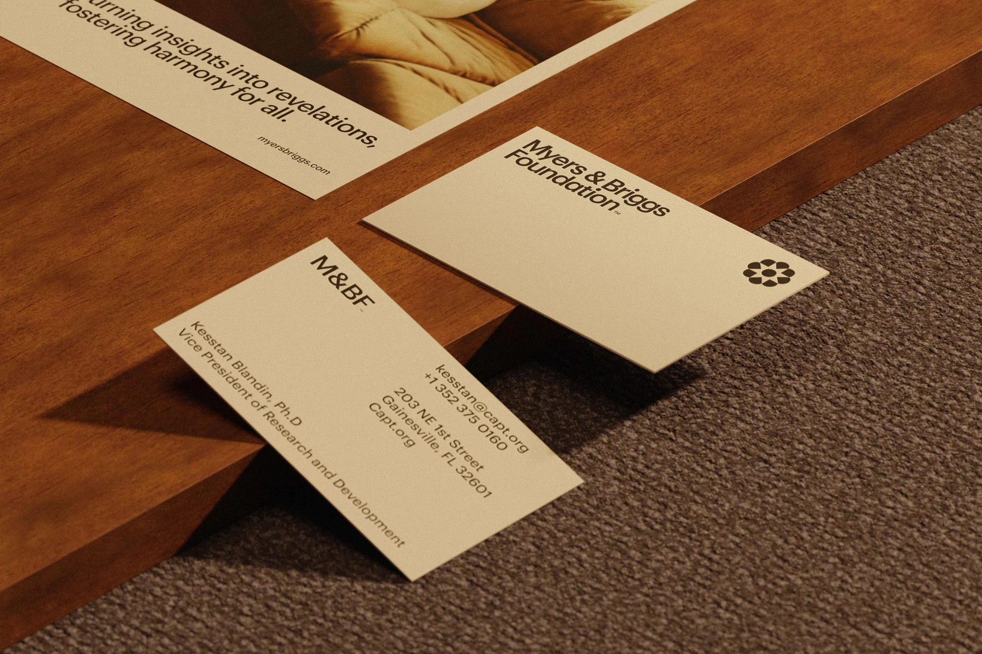 Close-up shot of Myers & Briggs Foundation business cards on a wooden and carpet surface featuring company branding and contact details.