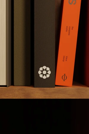 Close-up of book spines on a wooden shelf featuring a dark textured book with a white geometric emblem.
