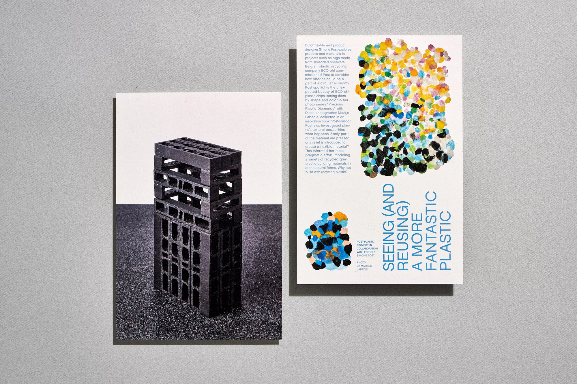 A black, multi-tiered, grid-like structure stands on a textured surface, accompanied by an informational poster with colorful accents.