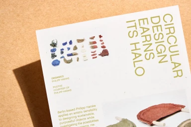 Printed design page featuring typography and small organic material samples on a textured tan background surface.