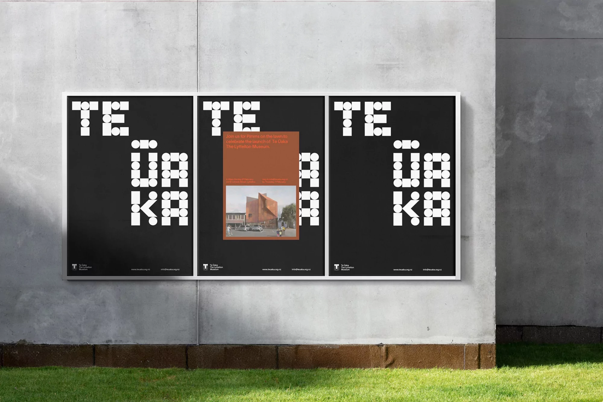 Eye-level shot of three posters with modern typography on a concrete wall next to a lawn with green grass on a bright day.