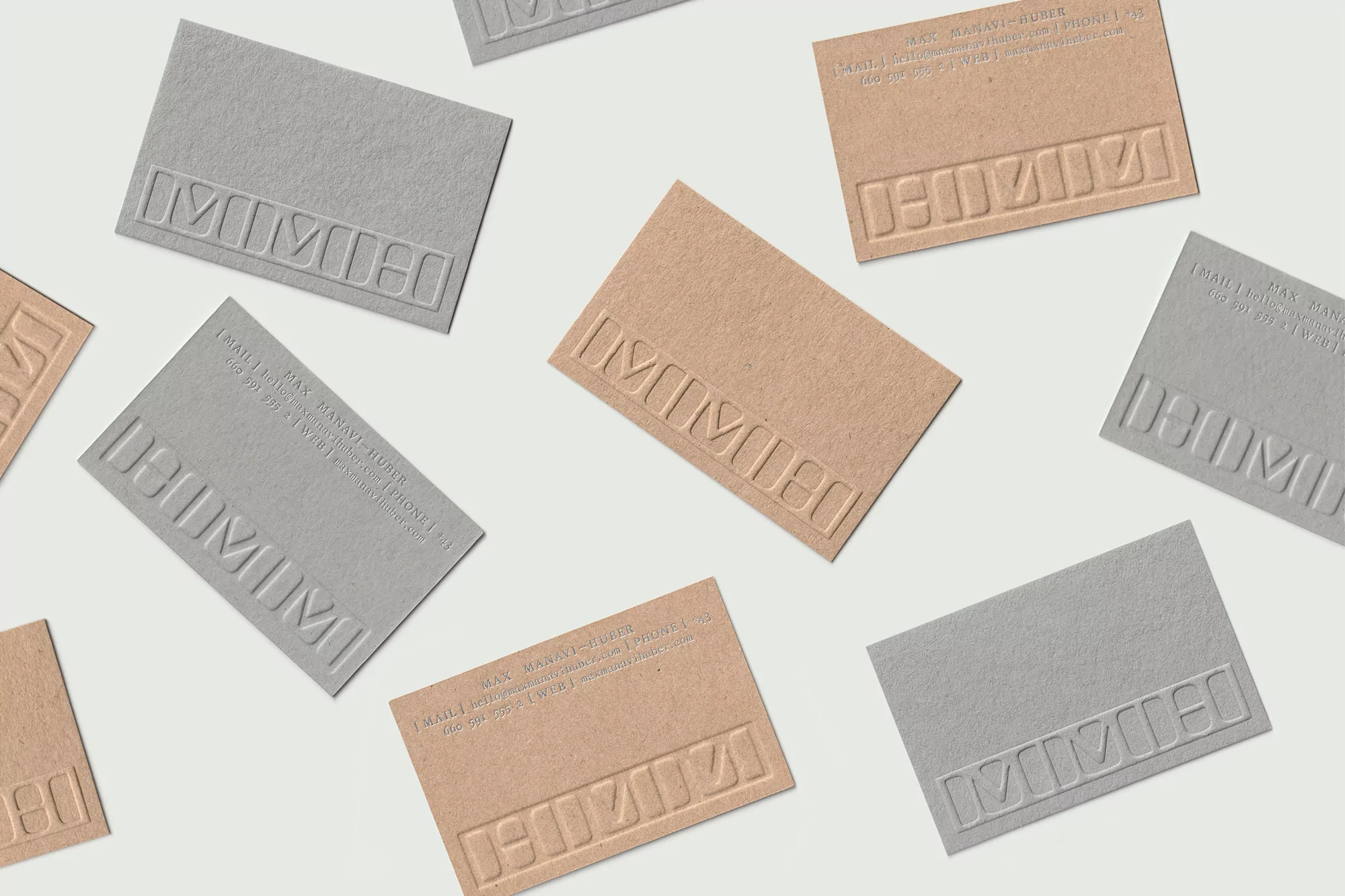 Scattered business cards in neutral tones with embossed text create a minimalist design on a plain background. Close-up, studio shot.