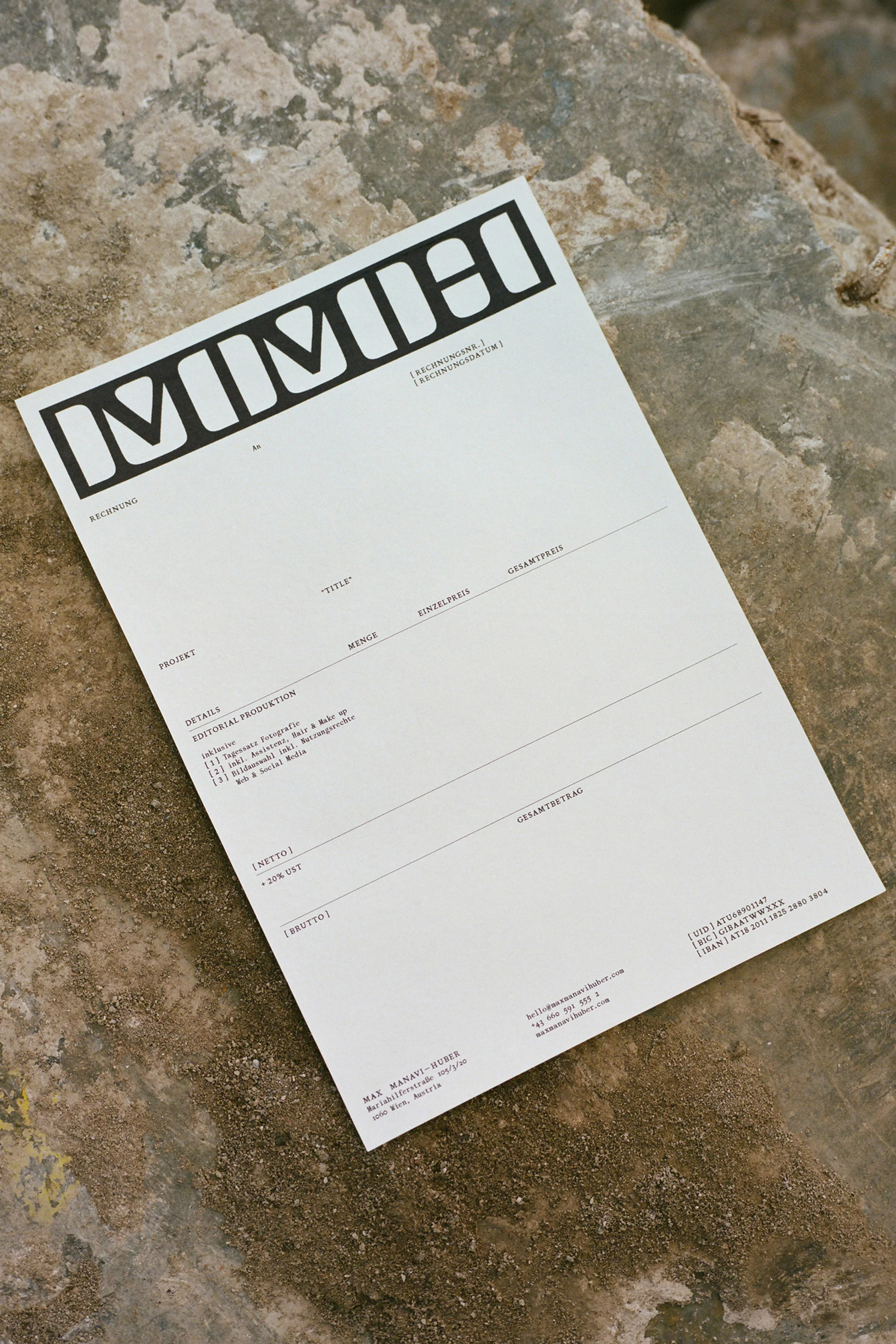Printed brand identity paper sheet with bold custom typography resting on rough stone background