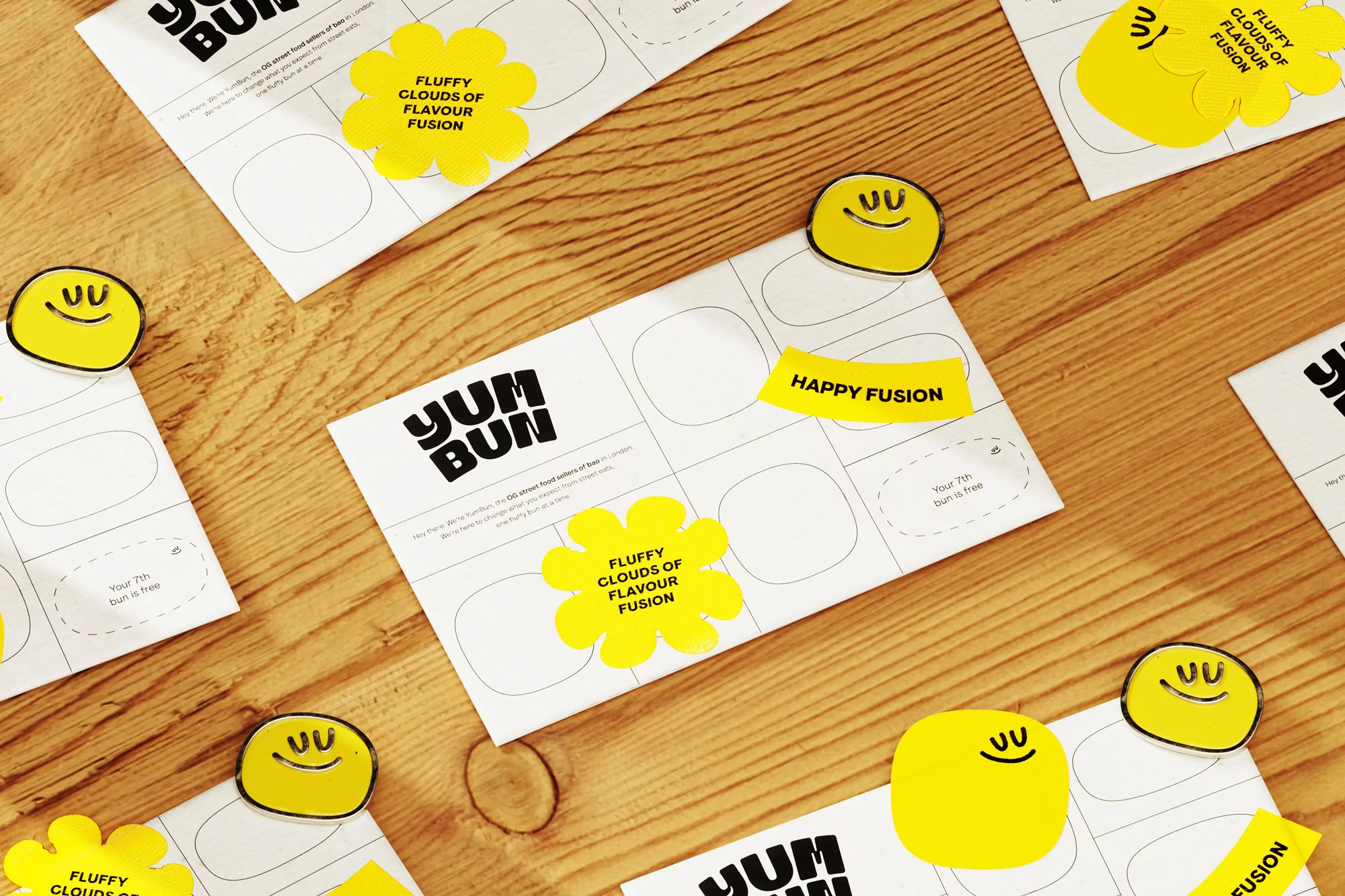 Overhead shot of Yum Bun branding materials on a wood surface including stickers, paper, and logo, creating a playful, food-related visual.