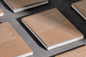Several paperback books with brown kraft paper covers and white typographic text arranged on a dark textured surface.