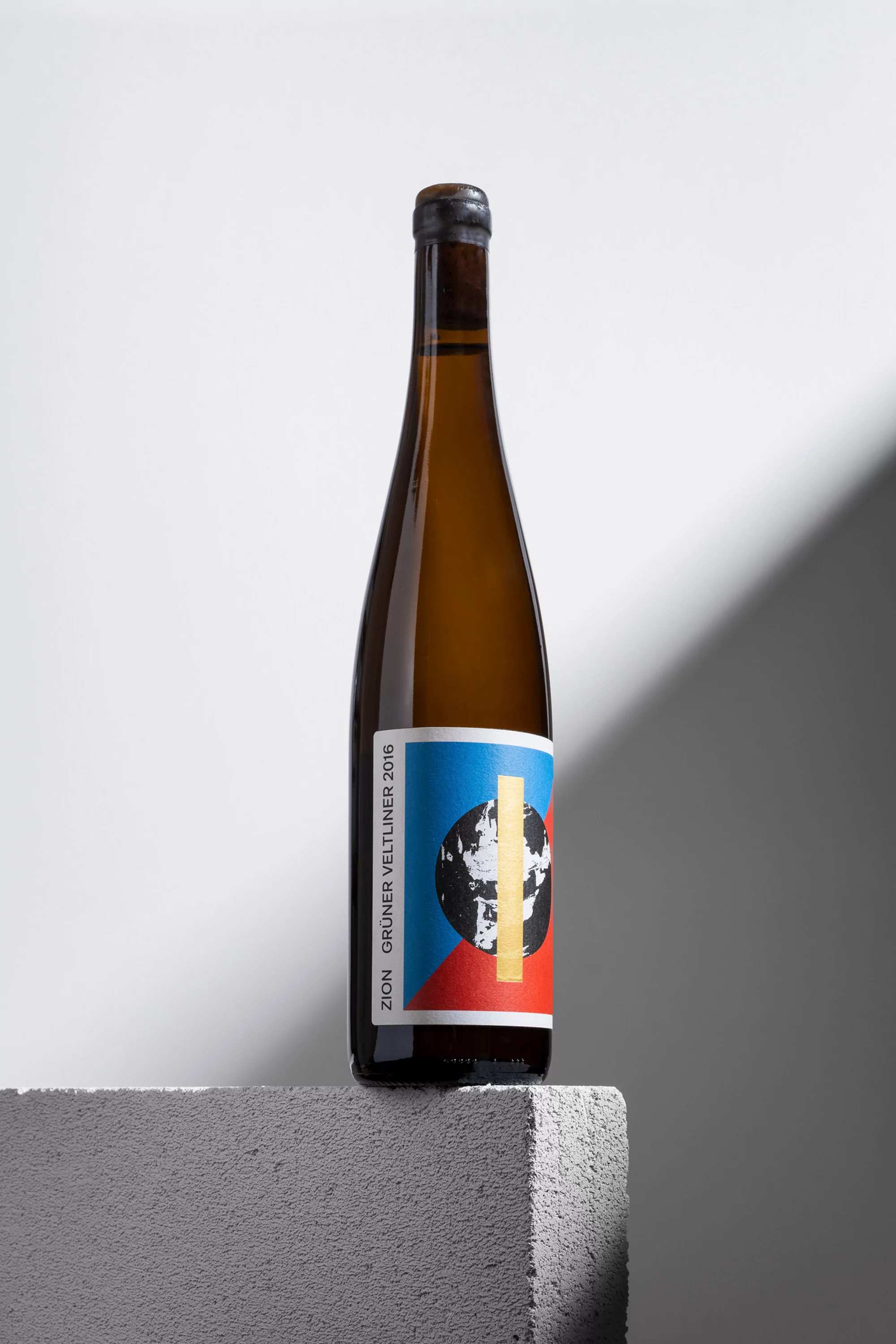 Wine bottle with abstract label resting on a concrete block against a grey and white studio backdrop