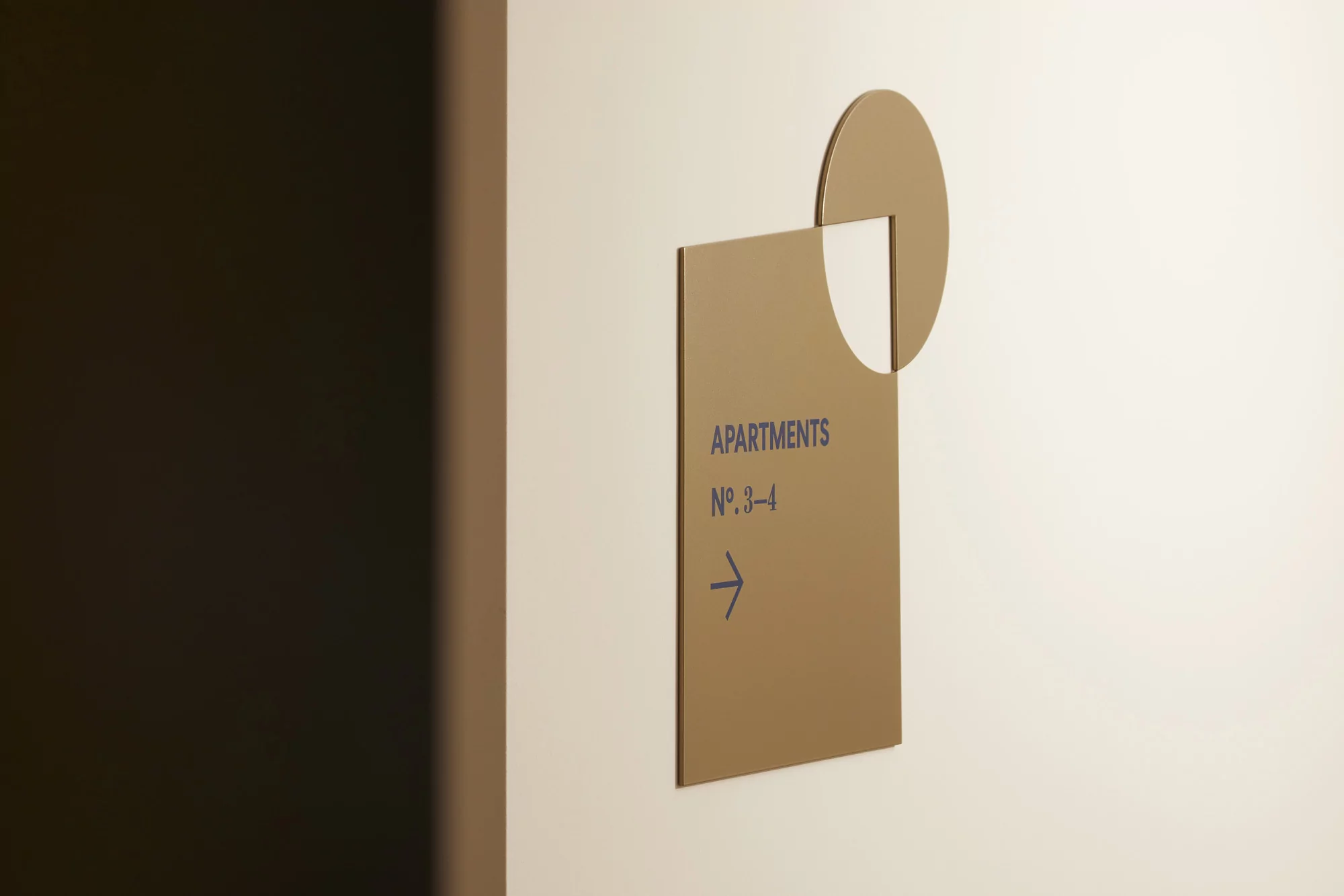 Indoor shot of a sign with the word 'Apartments' and a right-pointing arrow, suggesting directions for apartments number 3–4.