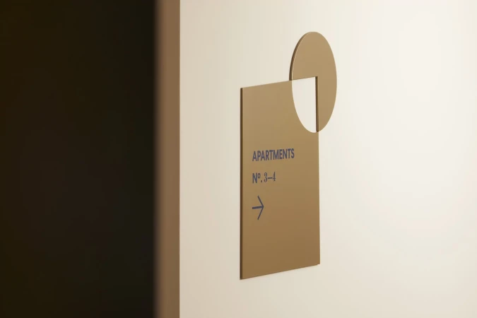 Indoor shot of a sign with the word 'Apartments' and a right-pointing arrow, suggesting directions for apartments number 3–4.
