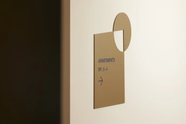 Apartments directional sign featuring geometric brass and blue typography on a white wall by DutchScot